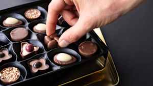 Ein Mann nimmt eine Praline aus einer Pralinenschachtel