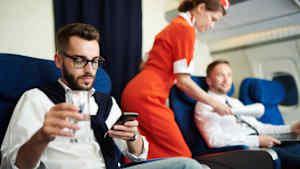 Fluggast arbeitet am Handy auf seinem Sitzplatz in der Businessclass