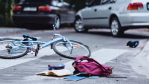 Unfallszene mit Fahrrad und Schulranzen und einem Auto