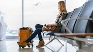 Eine Frau sitzt am Flughafen und sieht ihrem verpassten Flieger nach