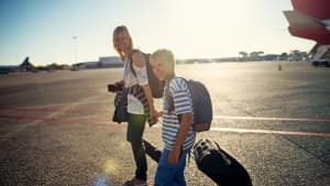 Mutter und Sohn gehen zu Flugzeug am Flughafen
