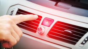 Eine Hand zeigt mit dem Zeigefinger auf den Schalter für den Warnblinker