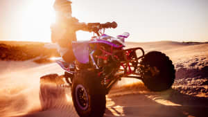 Ein Quadfahrer fährt über eine Sanddüne