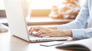 Frau tippt an einem Laptop