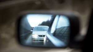 Im Außenspiegel ist ein nah auffahrendes Auto zu sehen