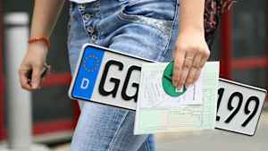 Junge Frau mit Kennzeichen auf dem Weg zum Ummelden ihres Fahrzeugs in der Zulassungsstelle