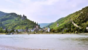 Blick über den Rhein auf Bad Bacherach im Sommer mit Stadtmauer und Burg Stahleck