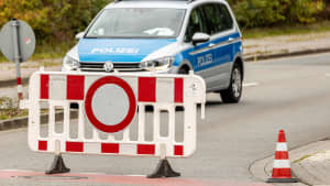Ein Einsatzfahrzeug der Polizei mit Blaulicht und Schriftzug hinter einer Absperrung