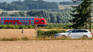 Ein Auto und ein Regionalexpress fahren nebeneinander