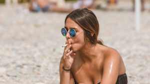 Eine junge Frau raucht am Strand von Nizza eine Zigarette