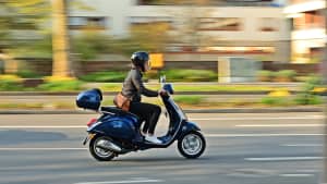 Eine Frau wird auf ihrer Vespa fährt durch die Stadt