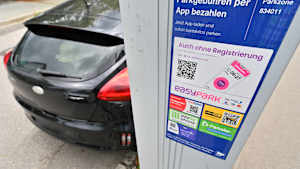 Am Straßenrand in der Innenstadt steht ein Parkscheinautomat. Im Hintergrund parkt ein Auto