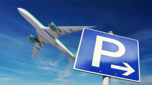 Ein Flugzeug fliegt über ein Parkplatzschild