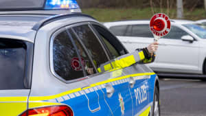 Ein Polizist hält die Polizeikelle aus dem Beifahrerfenster eines Polizeiautos heraus