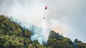 Ein Helicopter löscht einen brennenden Wald in Italien