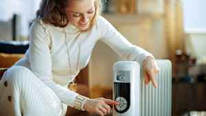 Eine frau bedient einen Ölradiator als Zusatzheizung in ihrem Wohnzimmer