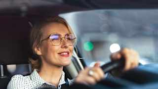 Lächelnde Business Frau fährt mit ihrem Auto durch die Stadt