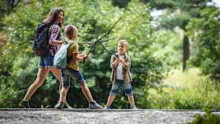 Eine Mutter mit ihren 2 Kindern auf einer Wanderung durch den Wald