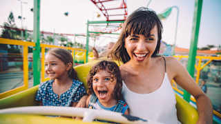 Frau fährt mit Kindern in der Achterbahn