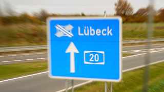 Ein blaues Straßenschild an einer Autobahn dass das Autobahnkreuz Lübeck anzeigt