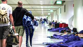 Menschen ruhen sich nach möglichen Drohnensichtungen am Flughafen München aus. Der Flughafen München hat am Abend wegen möglicher neuer Drohnen-Sichtungen wieder den Betrieb eingestellt.