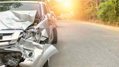 Beschädigtes silberes Auto bei Sonnenuntergang nach einem Unfall mit dem Leasingauto