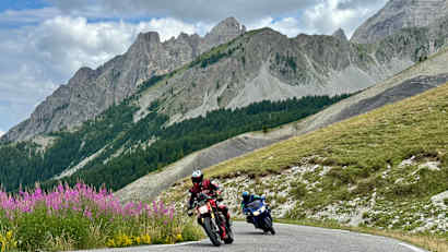 Motorradfahrer auf einer Straße am Col des Champs