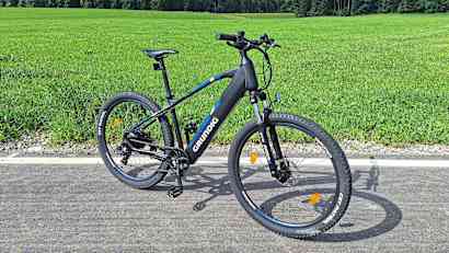 Seitliche Gesamtansicht des Grundig E275 E-Bikes vor einer Wiese.