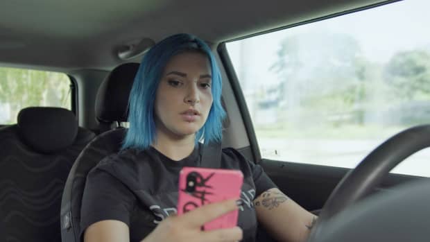 Junge Frau mit Handy am Steuer