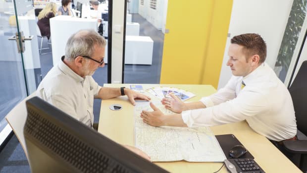 ADAC Touristik-Experte zeigt Mann sein Reiseziel auf einer Karte.