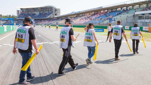 Sportwarte laufen in einer Reihe über die Start- und Zielgerade auf dem Hockenheimring