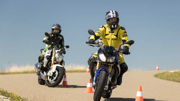 Zwei Motorradfahrer fahren hintereinander in Schlangenlinien um Pylonen.