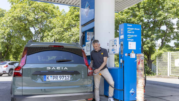 Ein Mann steht an einer Tankstelle neben dem LPG Dacia Jogger und betankt ihn mit LPGAutogas
