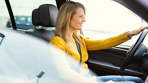 Frau sitzt lächelnd hinter Steuer eines Autos, nachdem sie ein ADAC Auto-abo abgeschlossen hat