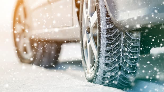 Winterreifen eines grauen Leasing-autos fahren im Schnee.