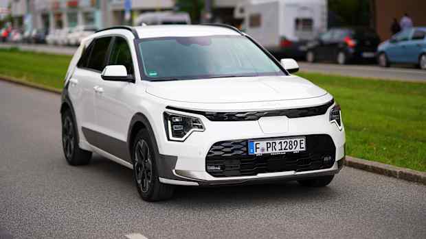 Ein weißer Kia fährt eine Straße entlang und testet die Reichweite des Elektroautos.