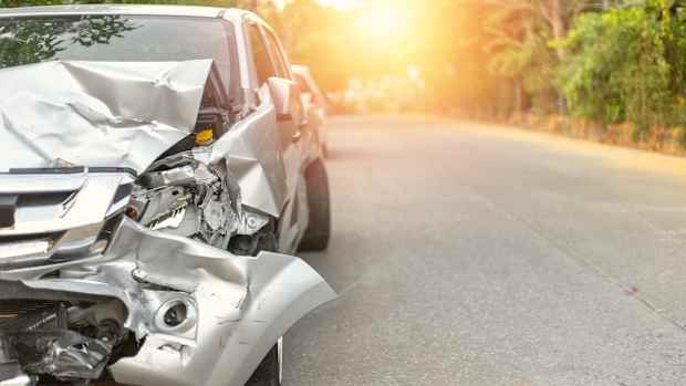 Beschädigtes silberes Auto bei Sonnenuntergang nach einem Unfall mit dem Leasingauto