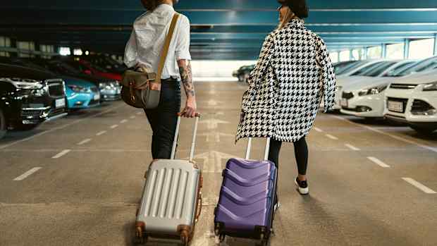 Pärchen geht in Parkhaus zu Mietwagen, nachdem sie die Mietwagenpreise verschiedener Anbieter verglichen hatten