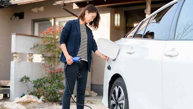 Eine Frau lädt ein Elektroauto vor einem modernen ADAC e-Charge Home auf.