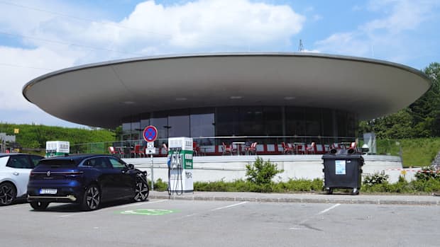 Ein blaues E-Auto steht im Urlaub auf dem Parkplatz eines Diners in Kärnten und wird an einer Ladestation aufgeladen.