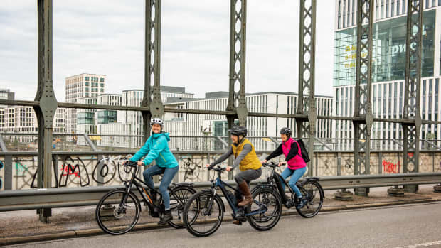 Drei Damen fahren im Winter mit dem E-Bike über eine Stahlbrücke.