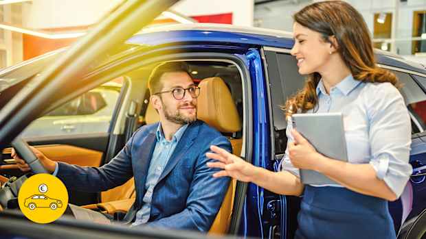 Autokunde in Neuwagen beim Autohändler mit Beraterin zur Neuwagen-Ausstattung.