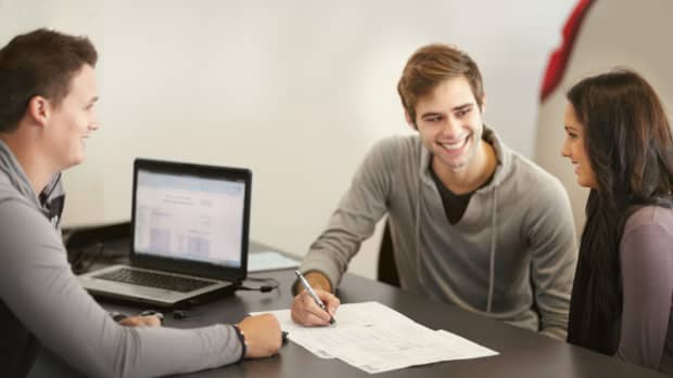 Mann und Frau sitzen an einem Tisch mit einem Mann der sie berät, ob Leasing oder Finanzierung besser ist.