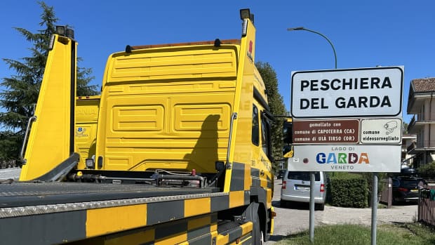 Ein ADAC-Transporter neben einem Ortsschild des Gardasees und ist bereit für einen Fahrzeugrücktransport