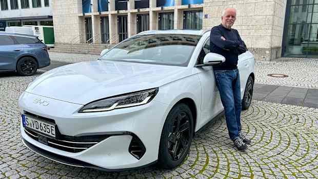 ADAC Redakteur Wolfgang Rudschies lehnt an einem BYD Seal 6 DMi Touring