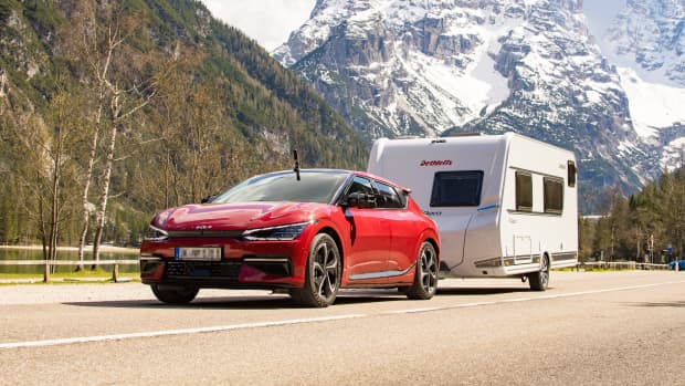 Elektroauto fährt mit einem Wohnwagen auf einer Straße