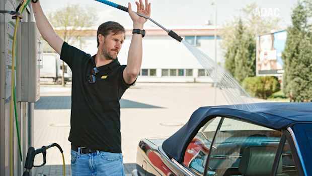 Ein ADAC Mitarbeiter reinigt ein Cabrio Dach
