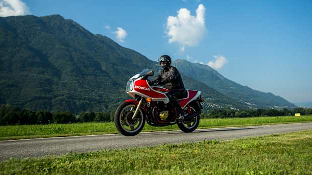 Ein Motorradfahrer fährt auf einer Landstraße vor einer Bergkulisse