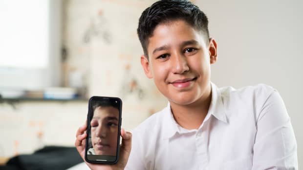 Leon Langenhorst hält ein Smartphone in der Hand auf dem man das entzündete Auge erkennen kann