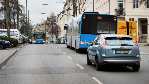 Ein Auto steht hinter einem Bus auf einer Strasse